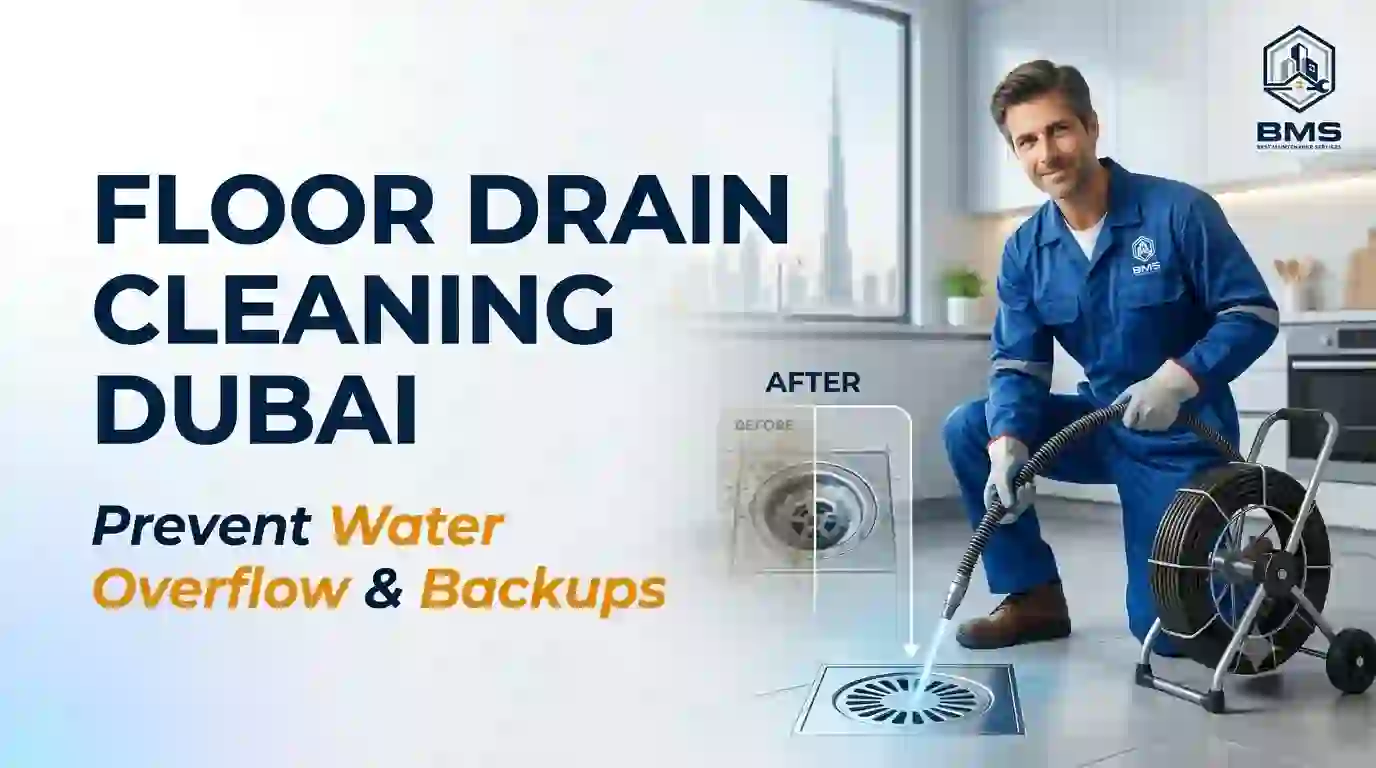 Professional Floor Drain Cleaning Dubai - Best Maintenance Services A professional plumber in a blue uniform and gloves uses a cleaning tool on a floor drain in a modern kitchen with a view of the Dubai skyline. The image features the text "Floor Drain Cleaning Dubai" and "Prevent Water Overflow & Backups," along with a b