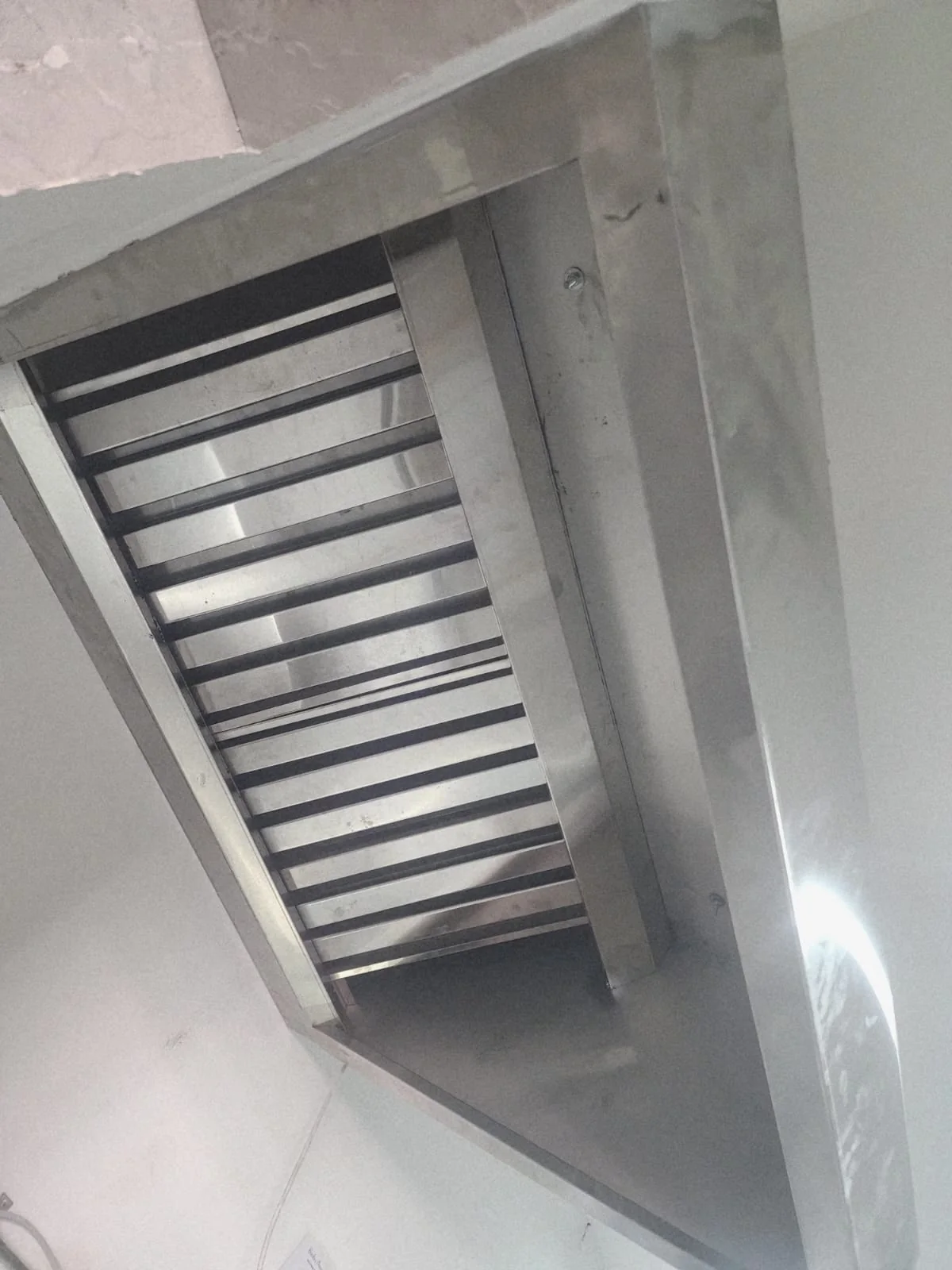 Installed commercial kitchen hood with stainless baffle-filter detail Installed commercial kitchen hood with stainless baffle-filter detail