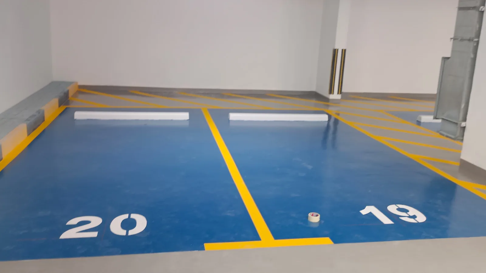 Blue epoxy parking bays with yellow boundaries and numbers