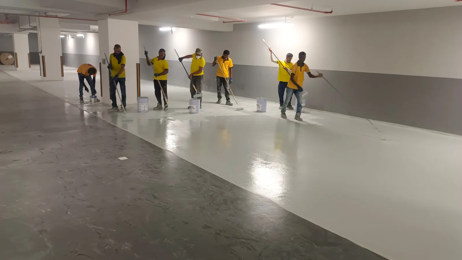 BMS team applying epoxy floor coating in a Dubai parking area